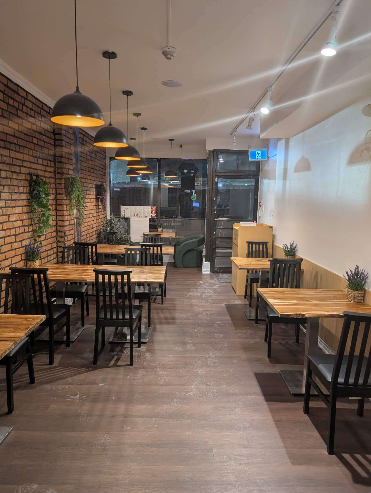 Cozy dining space with brick wall, wooden tables & pendant lights at Taki Sushi, a Japanese Restaurant in Toronto