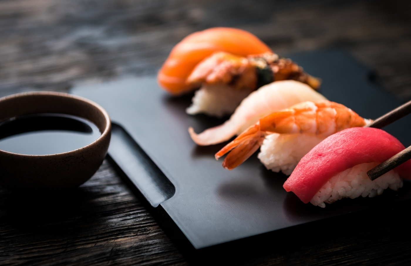 Assorted nigiri sushi beside a soy sauce bowl at Takumi Sushi, a Sushi Restaurant in Seattle