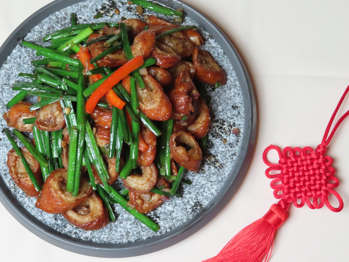 Stir - fried intestines with chives beside Chinese knot at Tang Pavilion, a Chinese Restaurant in New York