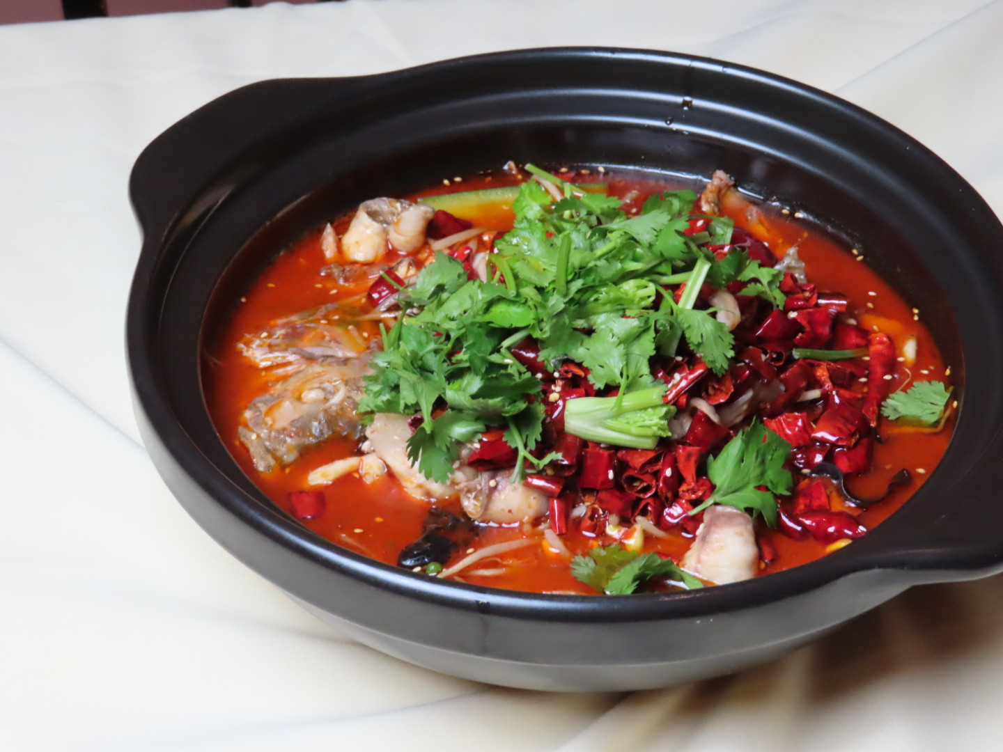 Spicy fish hot pot with chili peppers and cilantro at Tang Pavilion, a Chinese Restaurant in New York