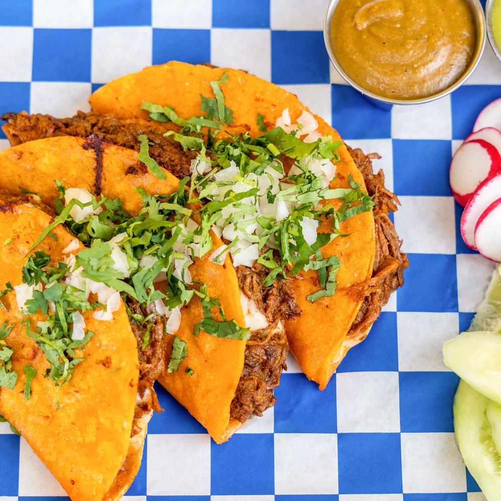 Birria tacos filled with shredded beef, onions and cilantro, served with dipping sauce Birria tacos filled with shredded beef, onions and cilantro, served with dipping sauce