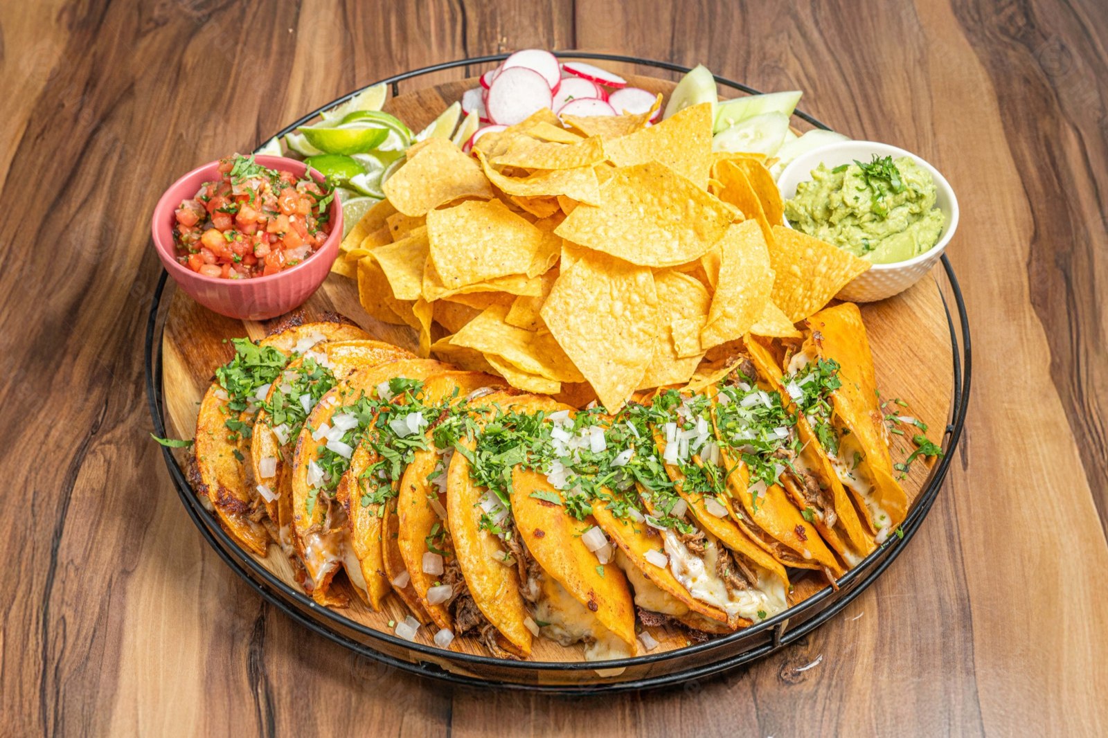 Birria tacos with melted cheese, onions and cilantro, served with tortilla chips, salsa, guacamole, radishes and lime