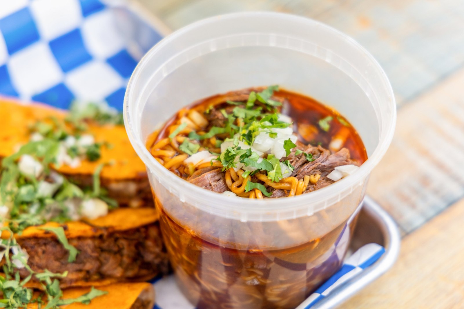 Birria ramen with shredded beef, noodles, onions and fresh cilantro served beside birria tacos Birria ramen with shredded beef, noodles, onions and fresh cilantro served beside birria tacos