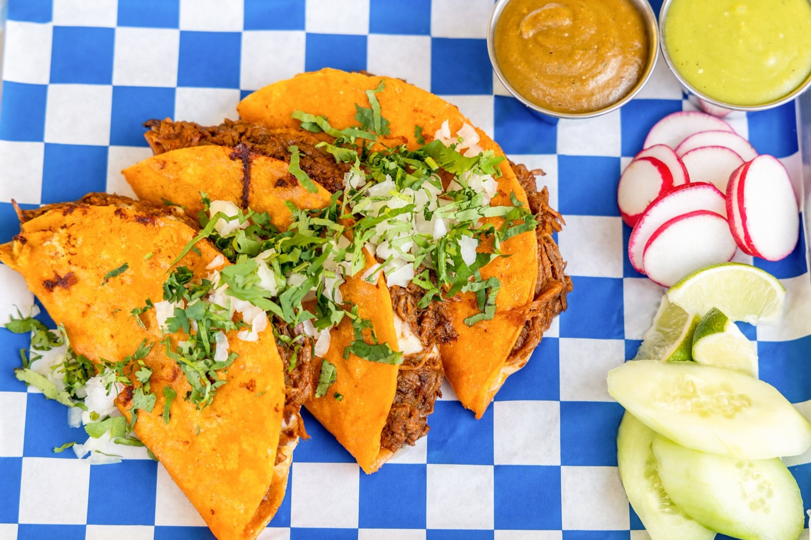 Birria tacos filled with shredded beef, onions and cilantro, served with dipping sauce Birria tacos filled with shredded beef, onions and cilantro, served with dipping sauce