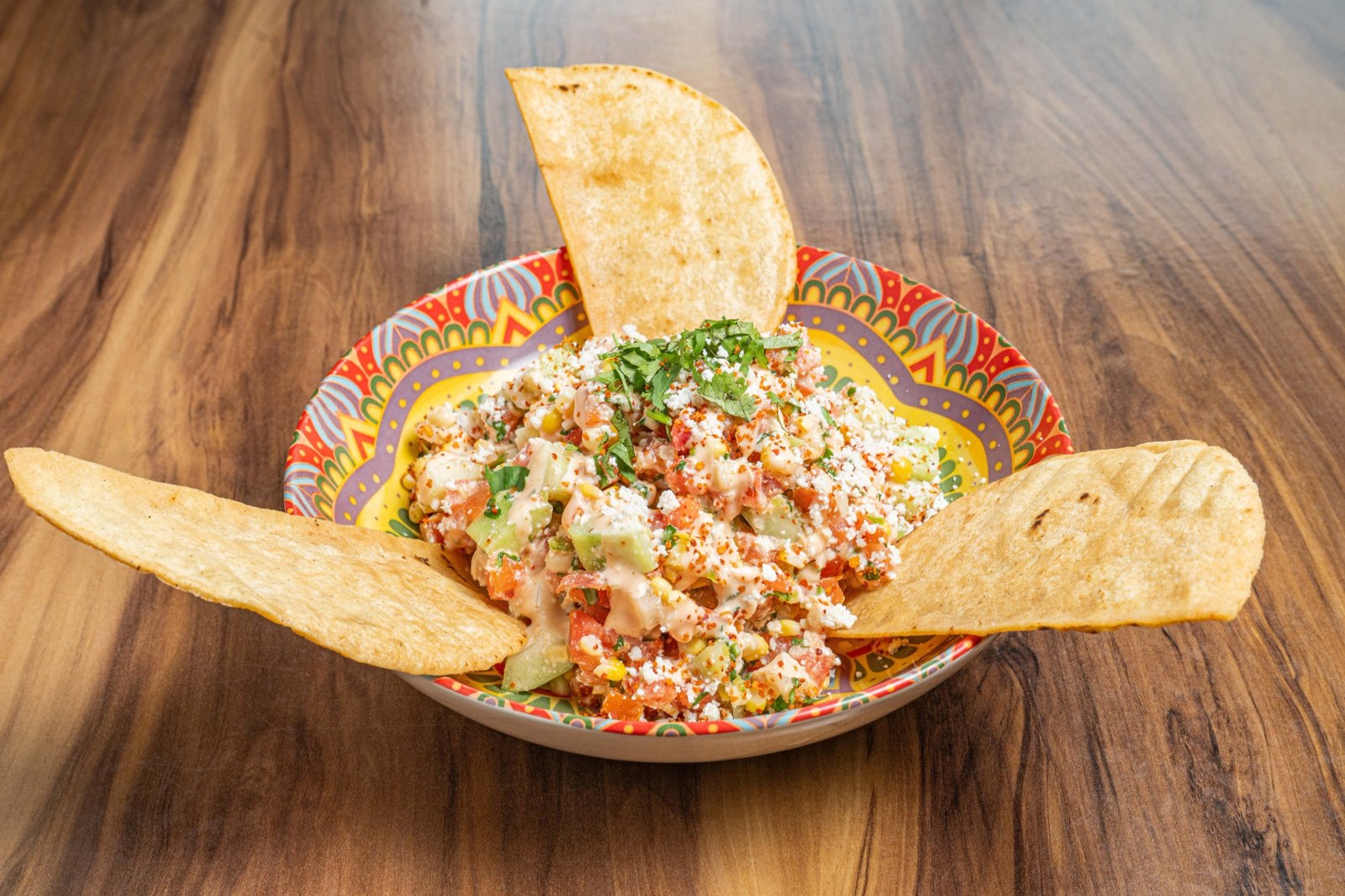Mexican corn salad topped with cheese cilantro and seasoning served with crispy tostadas