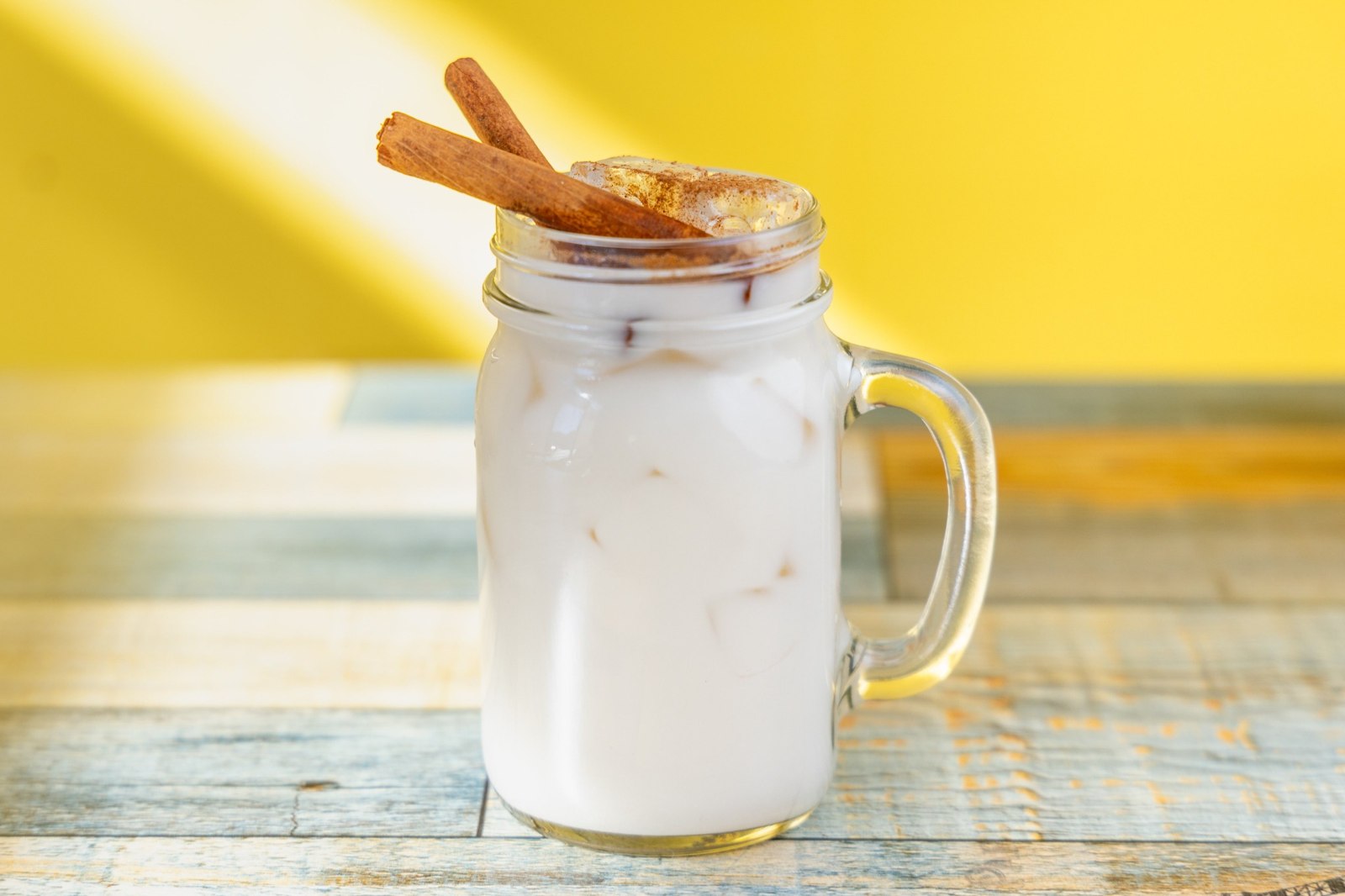 Iced horchata topped with cinnamon and garnished with cinnamon sticks
