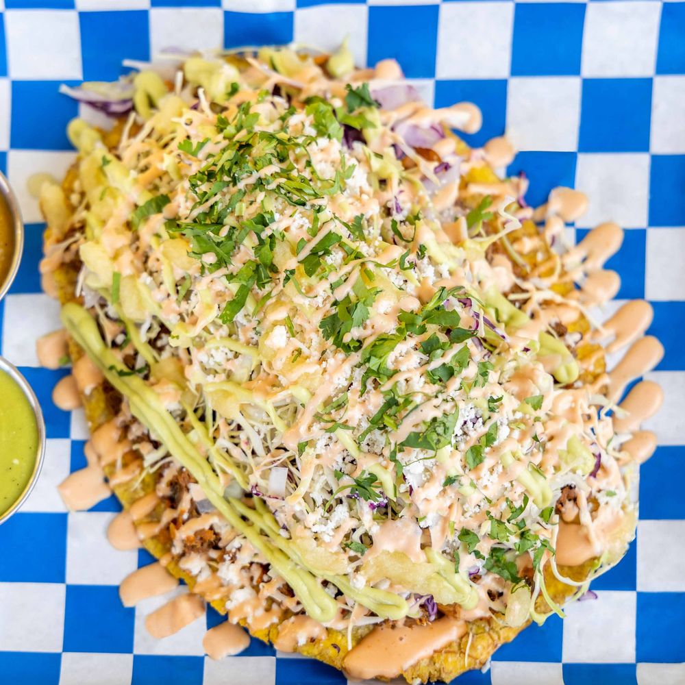 Patacon topped with shredded meat, cabbage, cheese, cilantro and creamy sauces Patacon topped with shredded meat, cabbage, cheese, cilantro and creamy sauces