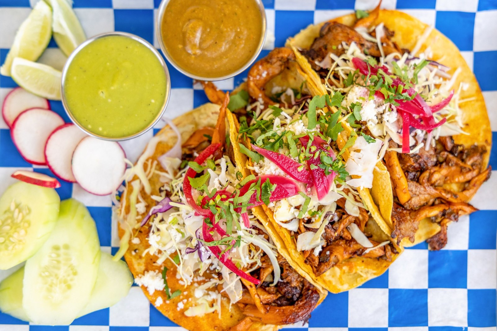 Tacos topped with shredded meat, cabbage, pickled onions, cheese and cilantro