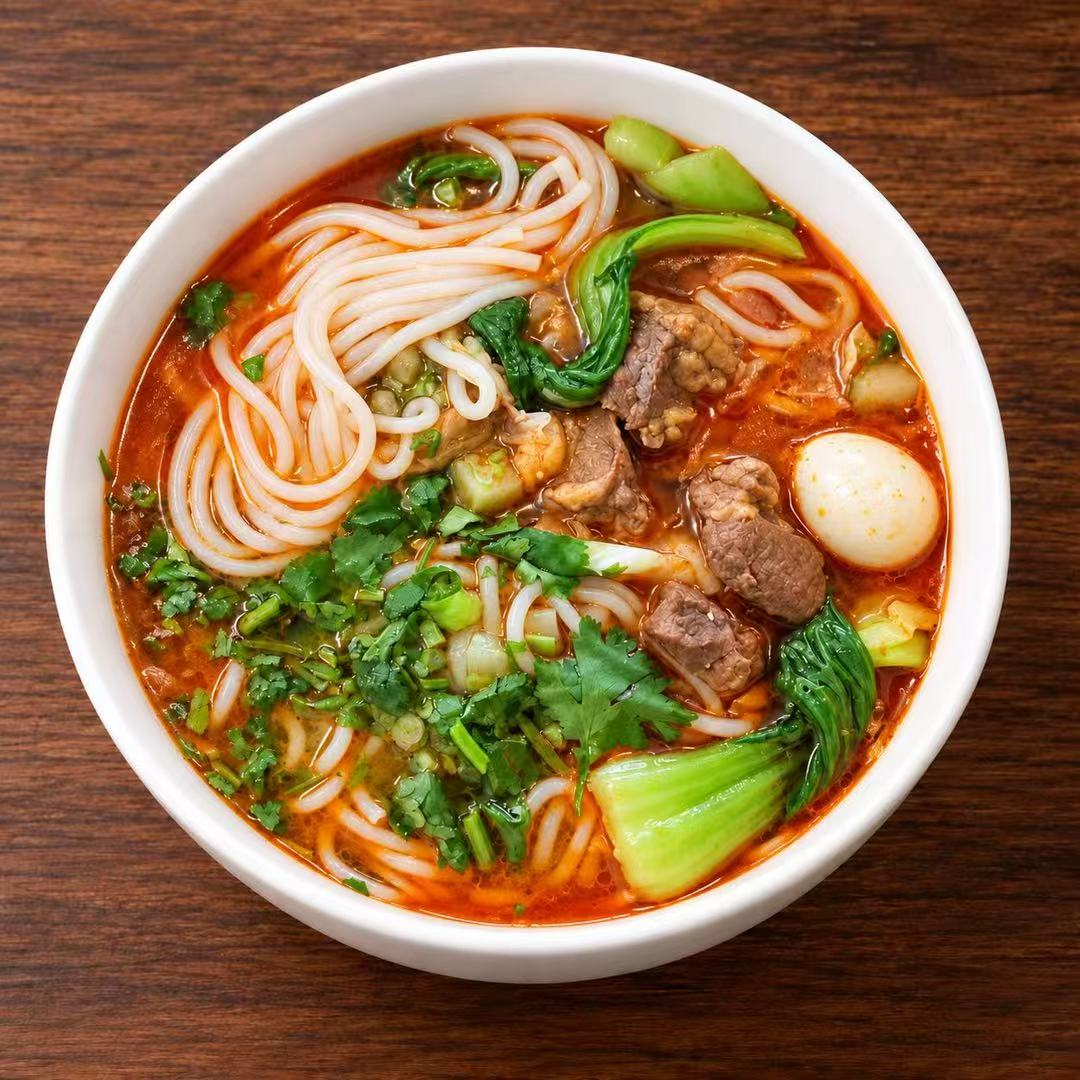 Spicy beef rice noodles with egg and leafy greens