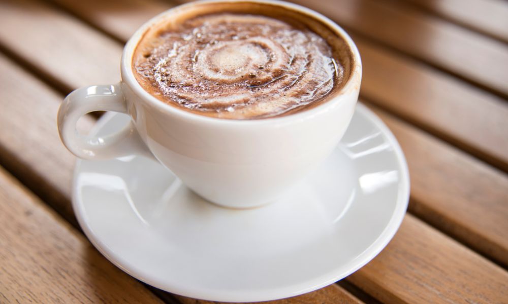 Hot cocoa topped with foam art in a white ceramic cup at Tea & Brown - Yellowstone, a Bubble Tea Store in West Yellowstone