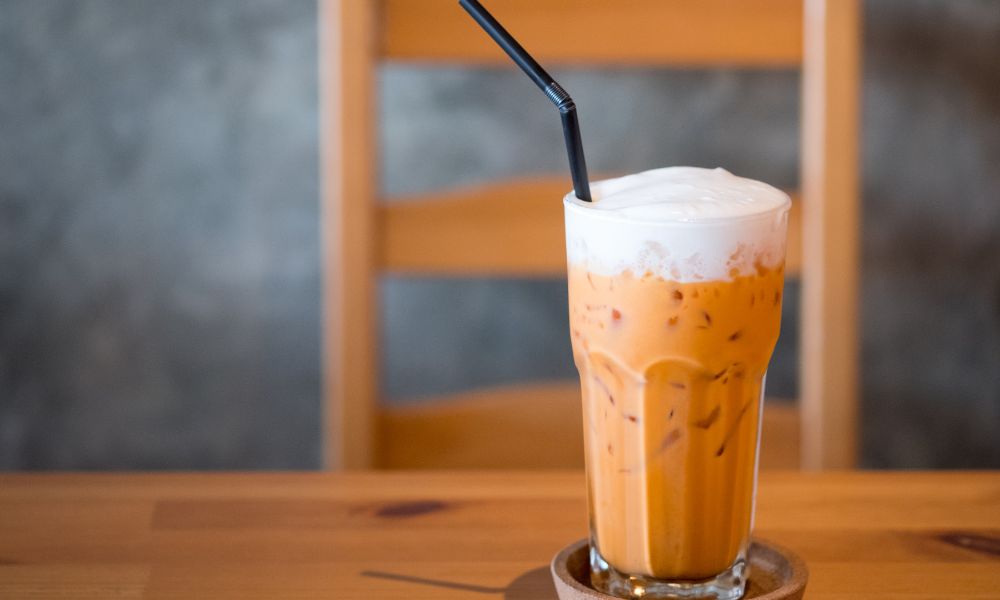 Thai iced tea with foam topping and black straw in a tall glass at Tea & Brown - Yellowstone, a Bubble Tea Store in West Yellowstone