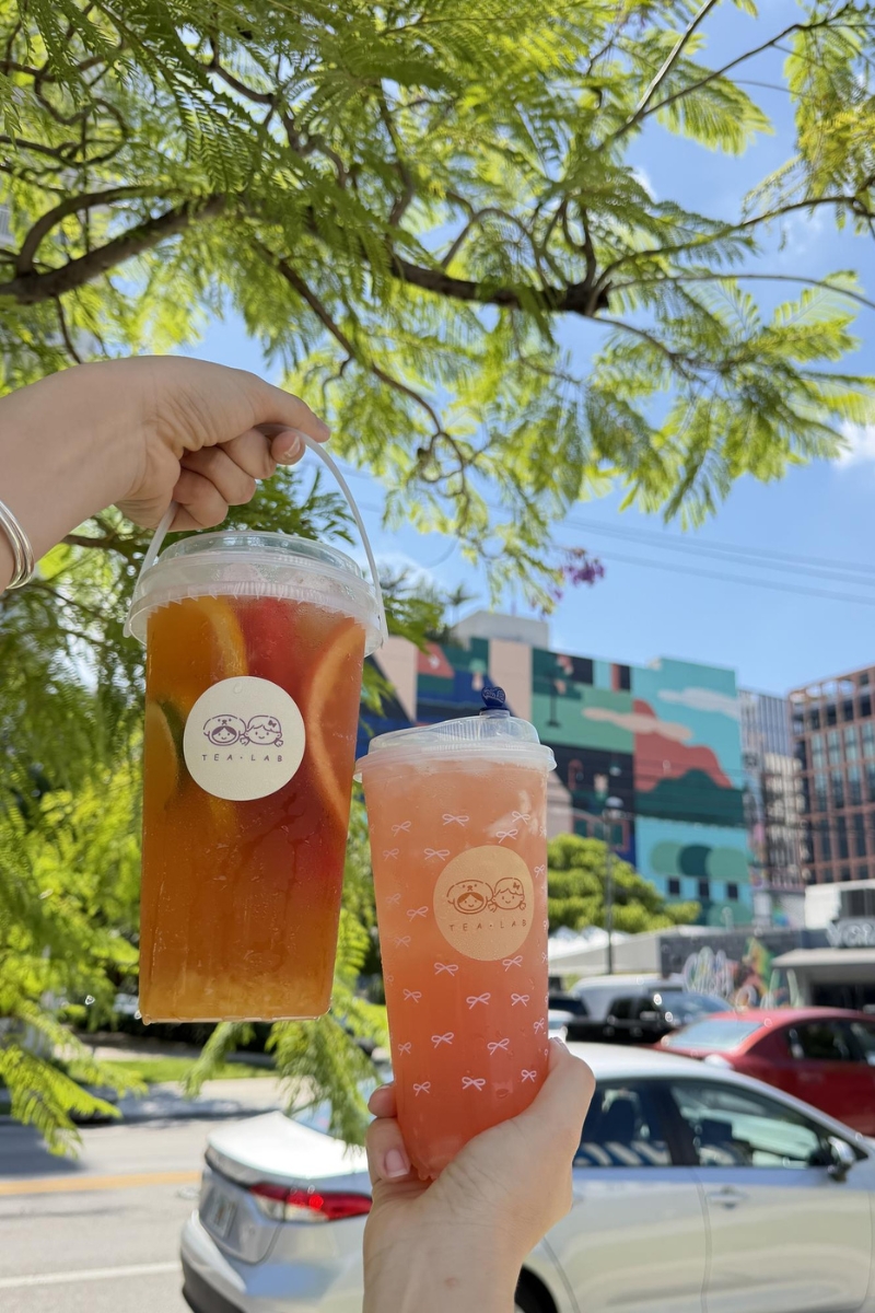 Two citrus fruit tea buckets under outdoor tree at Tea.Lab, a Bubble Tea Store in FL