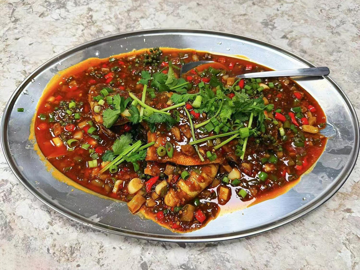Braised whole fish in spicy red sauce with herbs and chili peppers at Teng Jiao Wu 藤椒屋，a Chinese Restaurant in Flushing