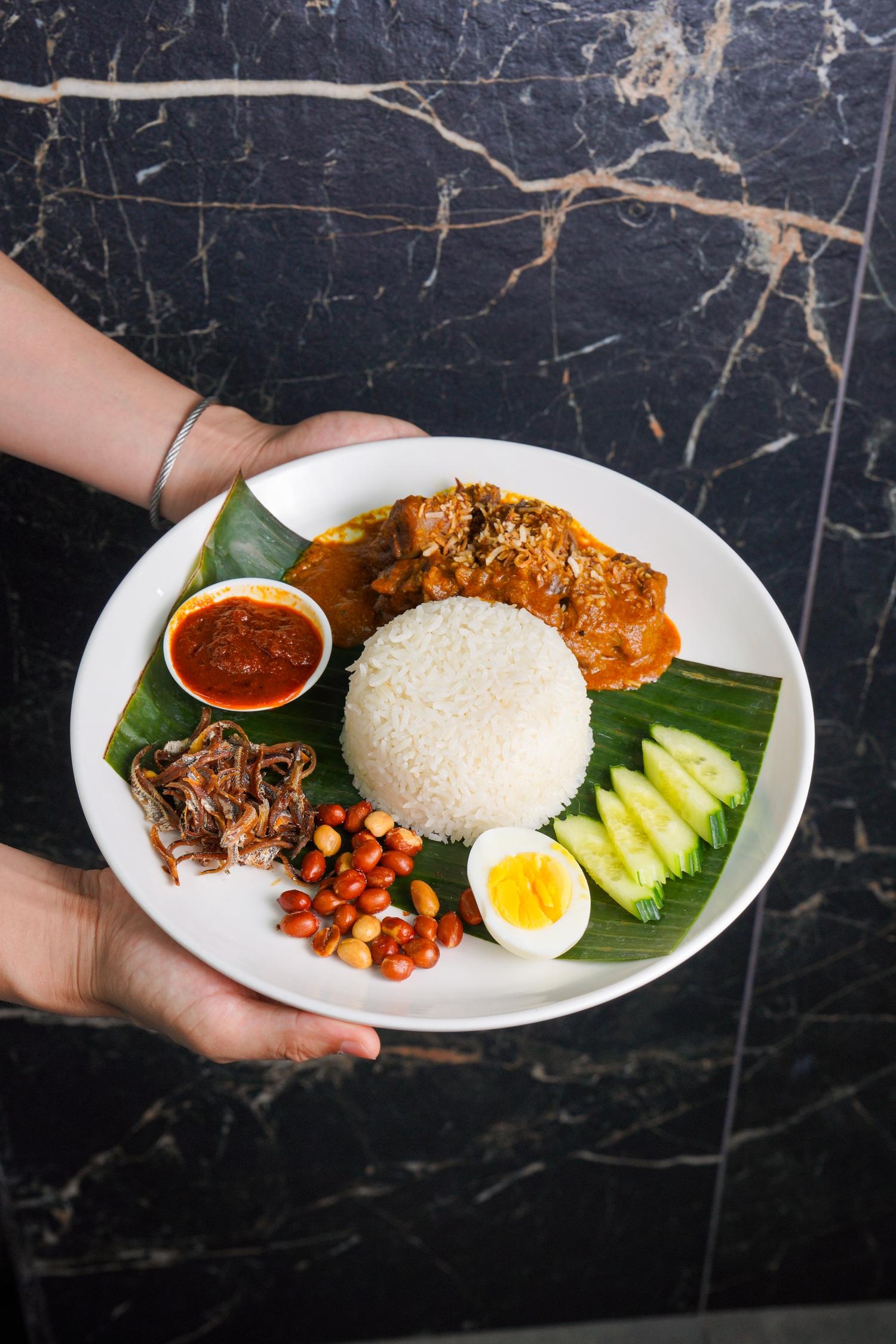 Served nasi lemak with curry chicken, peanuts and anchovies