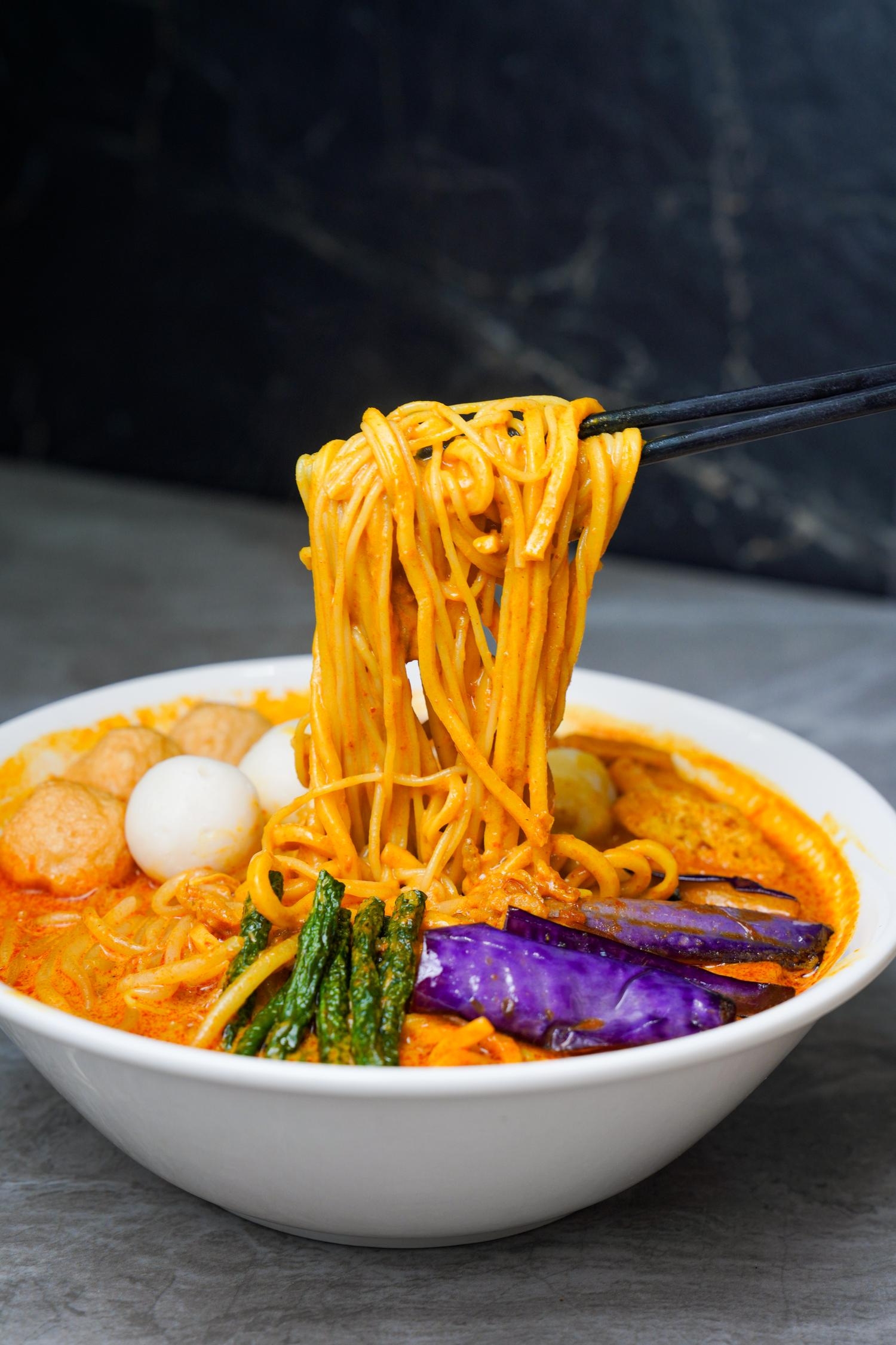 Thai curry noodle soup with fish balls, eggplant and yardlong beans