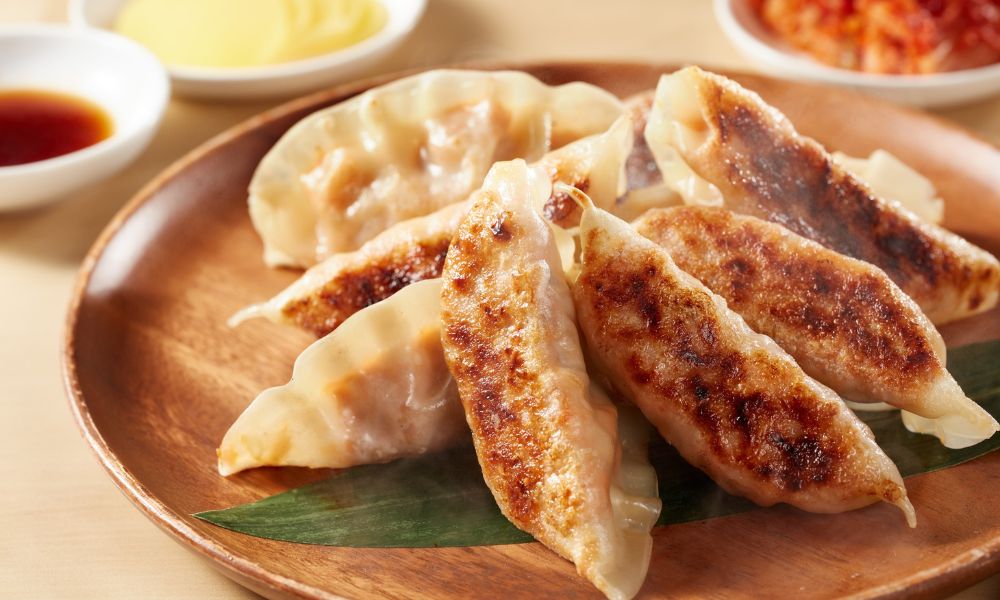 Pan-fried pork dumplings with crispy bottoms served on a wooden plate at The Imperial Treasure, a Chinese restaurant in Matthews