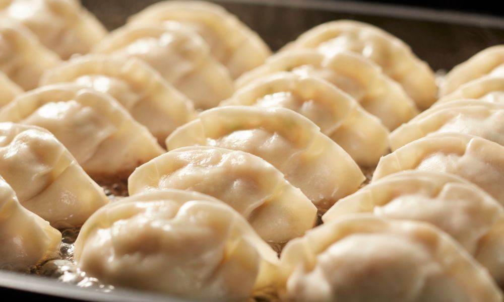 Steaming pot of pan-fried dumplings cooking on a hot griddle at The Imperial Treasure, a Chinese restaurant in Matthews