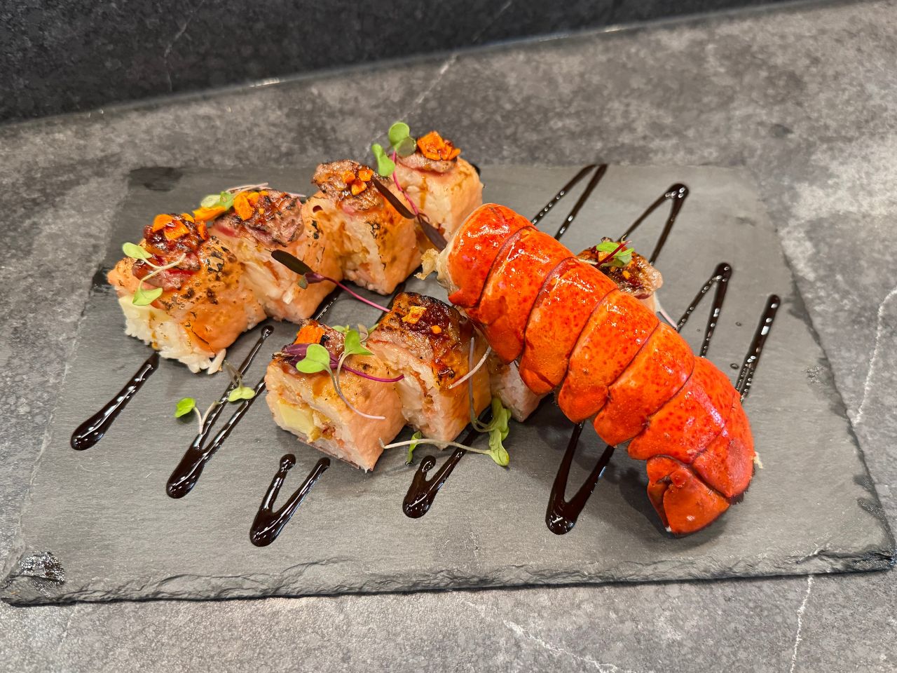 The-Shoya-Japanese-Restaurant-Lobster-Sushi-Roll-Pleasant-Hill Sushi roll with lobster tail and savory toppings on slate at The Shoya, a Japanese Restaurant in Pleasant Hill