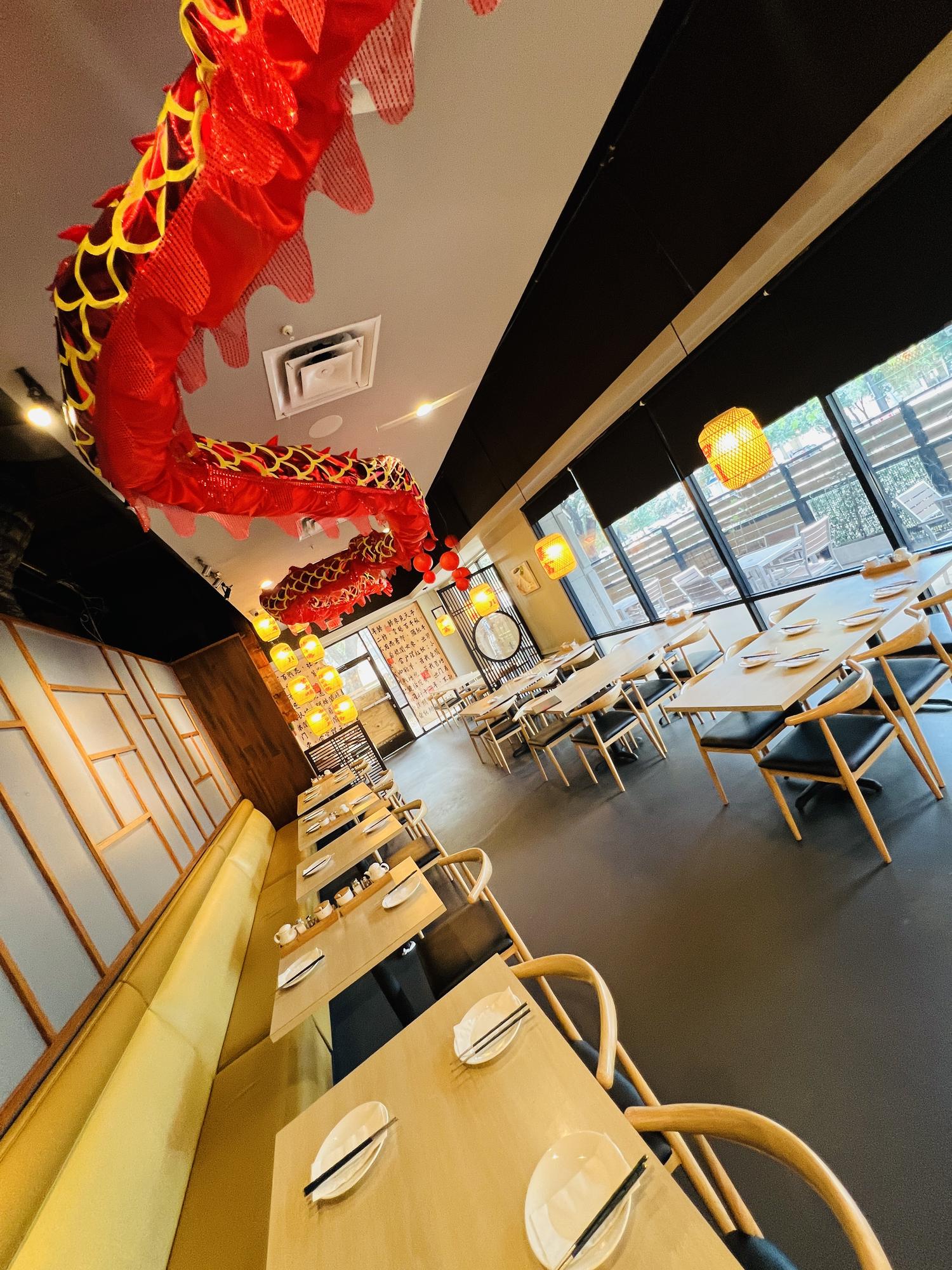 Modern dining area with red dragon decor, wooden tables, and large windows letting in natural light.