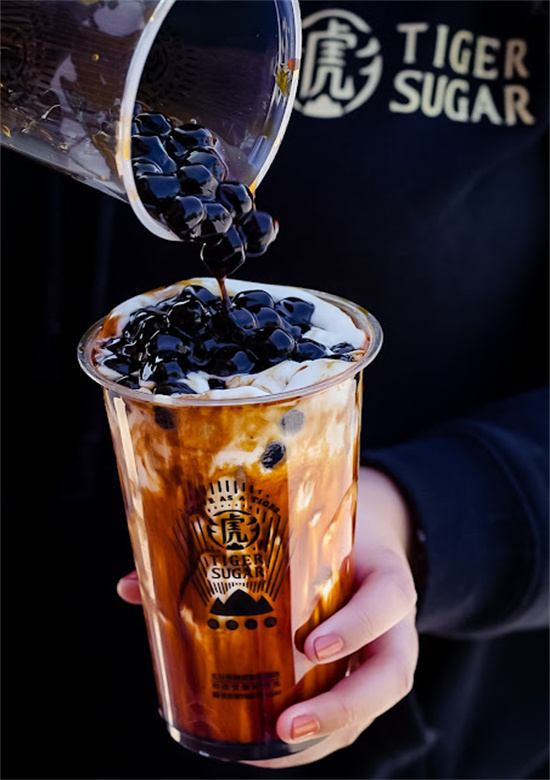 Worker pouring black tapioca pearls onto brown sugar bubble tea at Tiger Sugar, a Bubble tea store in Philadelphia