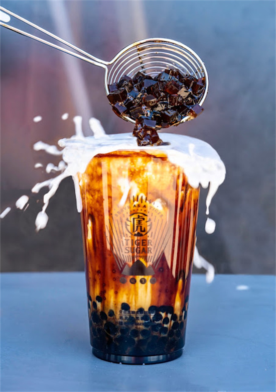 Scoop dropping jelly cubes onto bubble tea with milk splash at Tiger Sugar, a Bubble tea store in Philadelphia