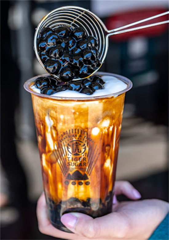 Metal scoop adding black tapioca pearls onto brown sugar bubble tea at Tiger Sugar, a Bubble tea store in Philadelphia
