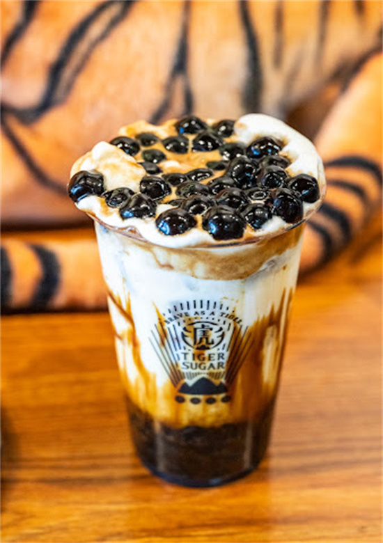 Brown sugar boba milk tea topped with tapioca pearls on wooden table at Tiger Sugar, a Bubble tea store in Philadelphia