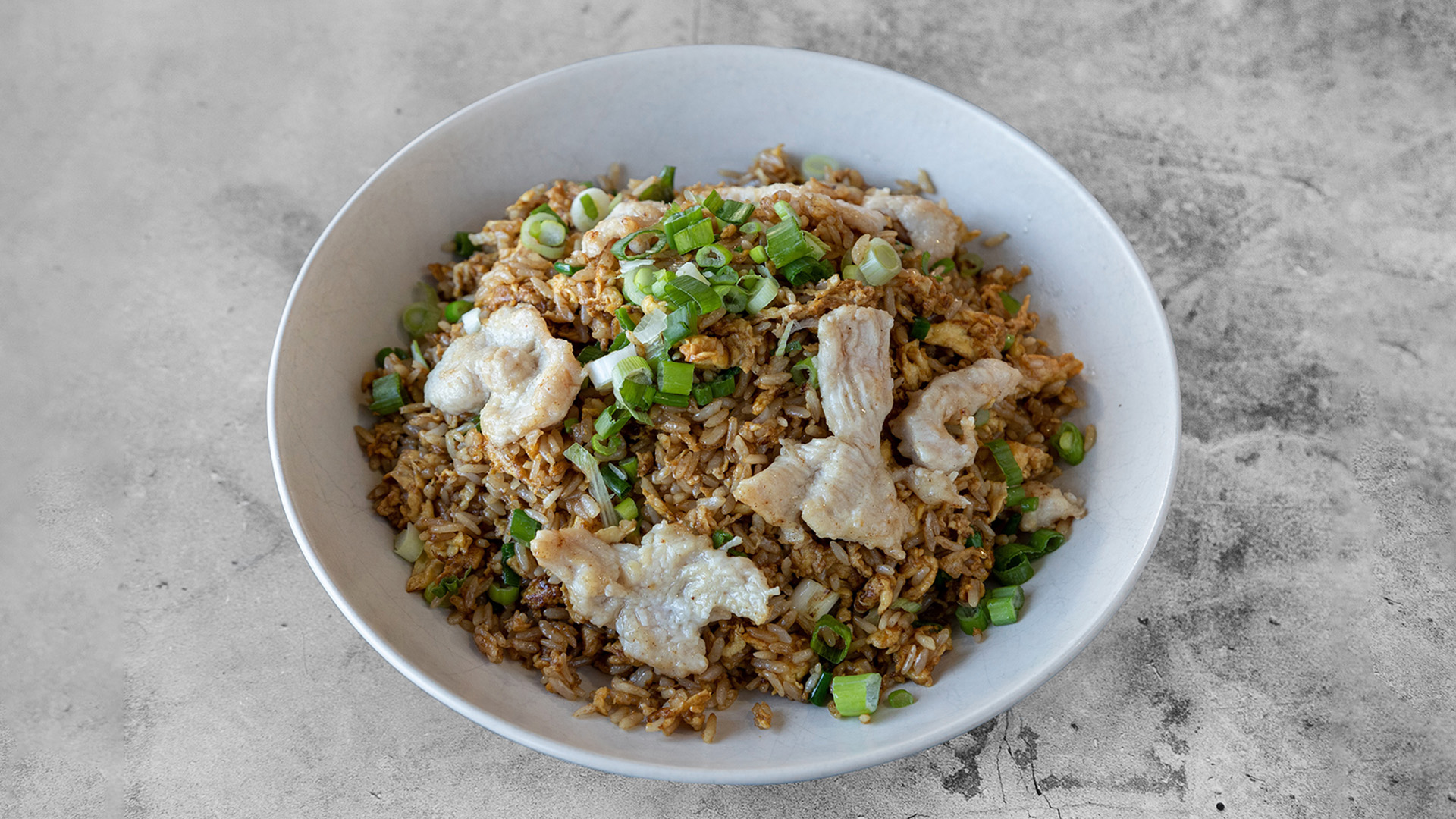 Chicken fried rice garnished with tender chicken slices and fresh chopped green onions in simple white ceramic bowl at Mandarin Chinese & Japanese Cuisine , a Chinese Restaurant in Santa Monica