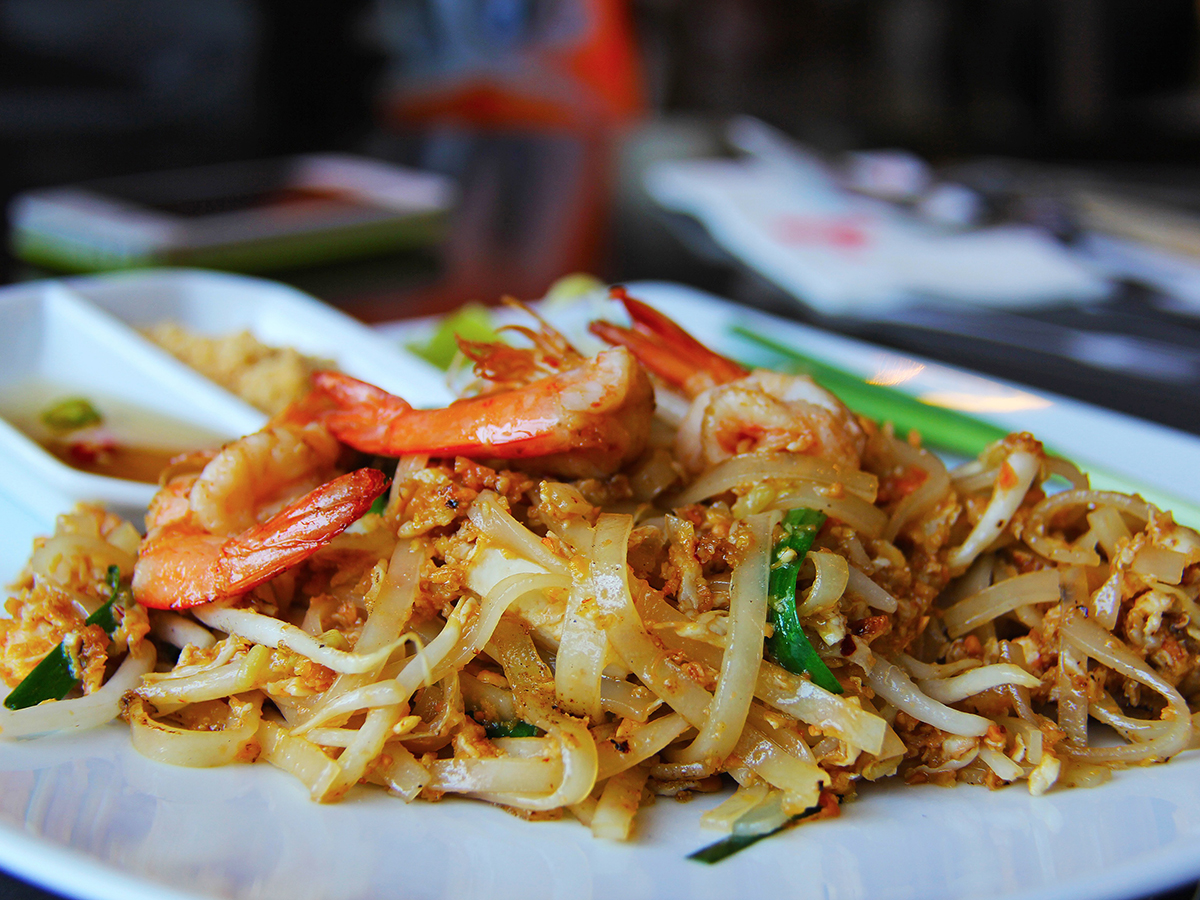 Pad thai rice noodles topped with large cooked shrimp, green onion and side dipping sauce on white rectangular plate at Mandarin Chinese & Japanese Cuisine , a Chinese Restaurant in Santa Monica Pad thai rice noodles topped with large cooked shrimp, green onion and side dipping sauce on white rectangular plate at Mandarin Chinese & Japanese Cuisine , a Chinese Restaurant in Santa Monica