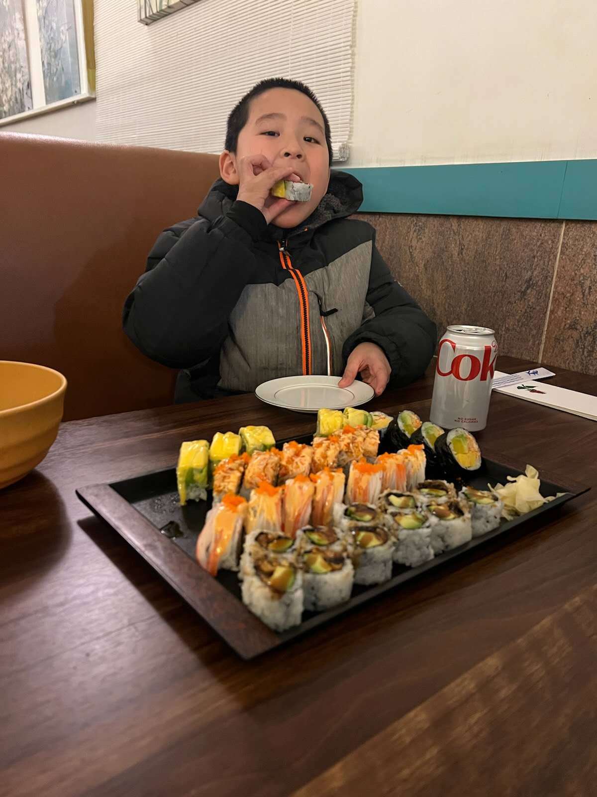 A boy eating a sushi roll with a platter of sushi at Tokyo Sushi and Hibachi, a Japanese restaurant in Terryville