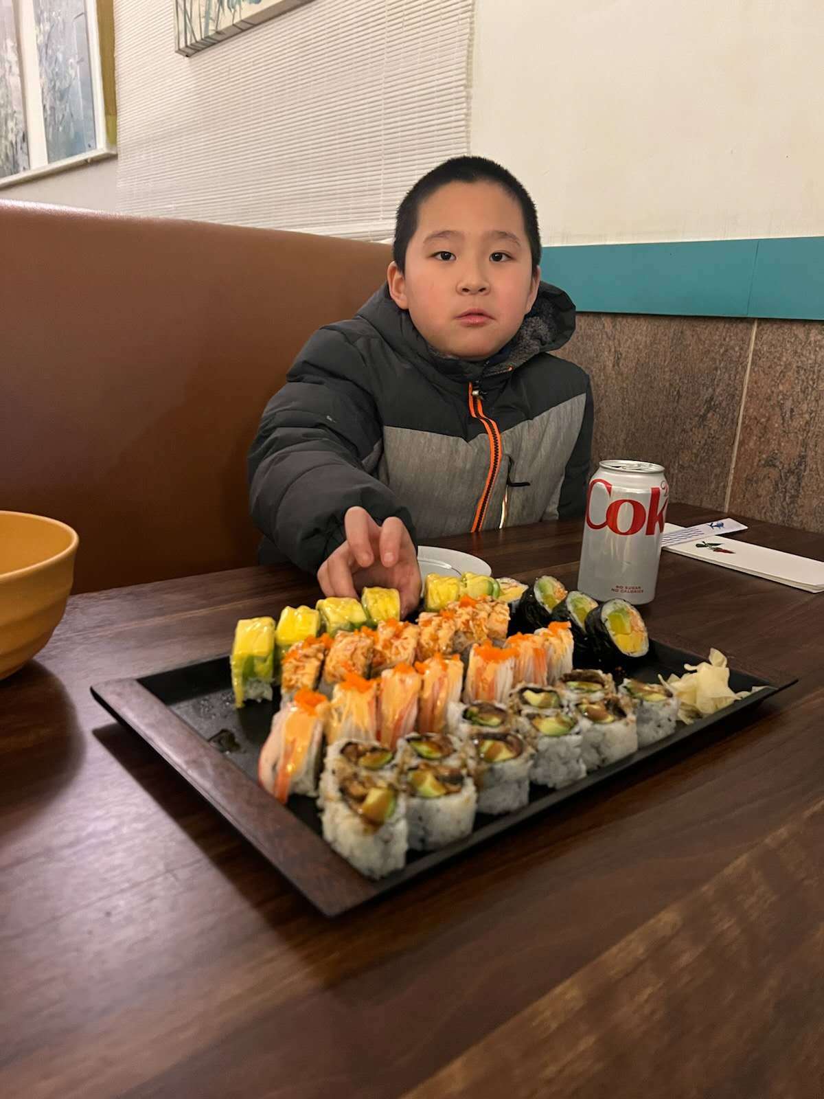 A boy reaching for sushi from a platter at Tokyo Sushi and Hibachi, a Japanese restaurant in Terryville