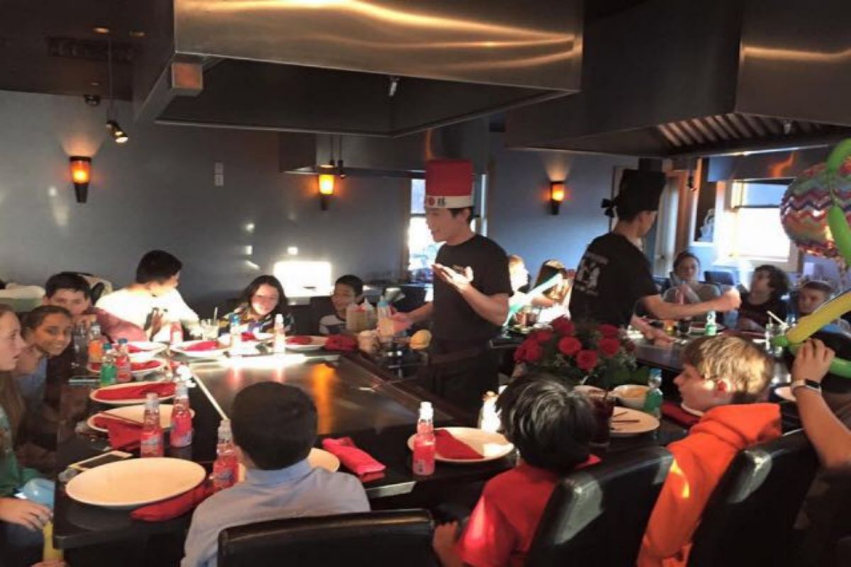 Two chefs entertaining guests around teppanyaki table at Tony's Sushi & Steakhouse, a Japanese Restaurant in East Moriches