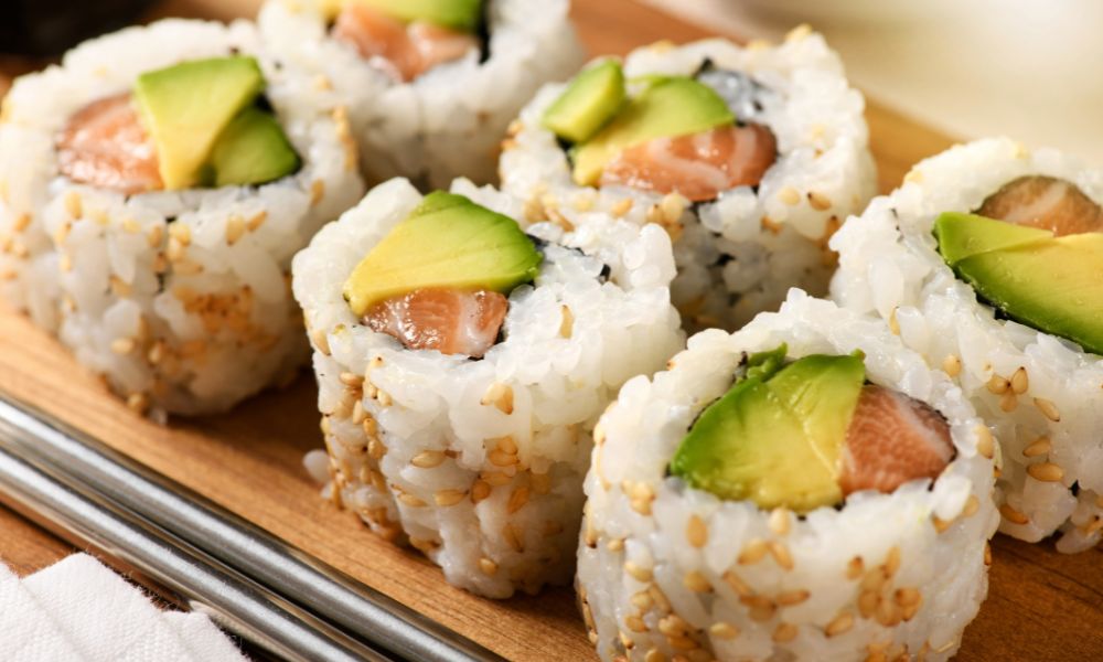 Salmon avocado sushi rolls with sesame seeds on a wooden board at Toro 7 Sushi, a Sushi Restaurant in New York