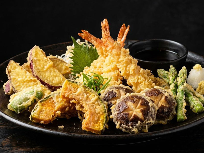 Black ceramic plate of assorted vegetable and shrimp tempura with small soy sauce dipping bowl at Toromi Sushi , a Sushi Restaurant in West Covina