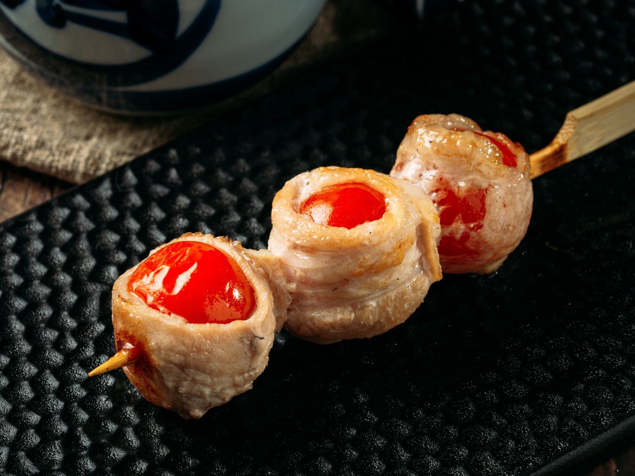 Grilled pork belly skewer with cherry tomatoes at Tosakko Ramen & Yakitori, a Japanese Restaurant in Pasadena