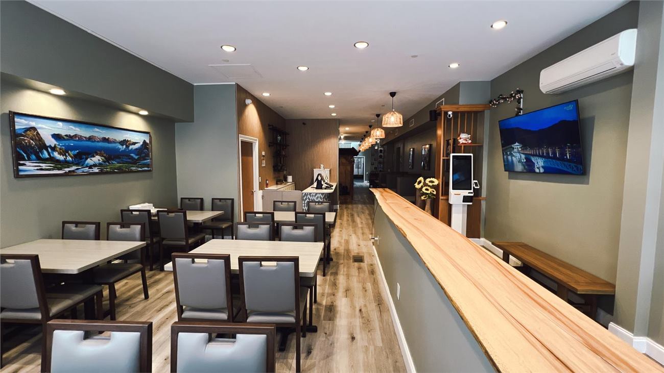 Modern Trio Cuisine dining room with tables, wall art, self-order kiosk, and warm lighting