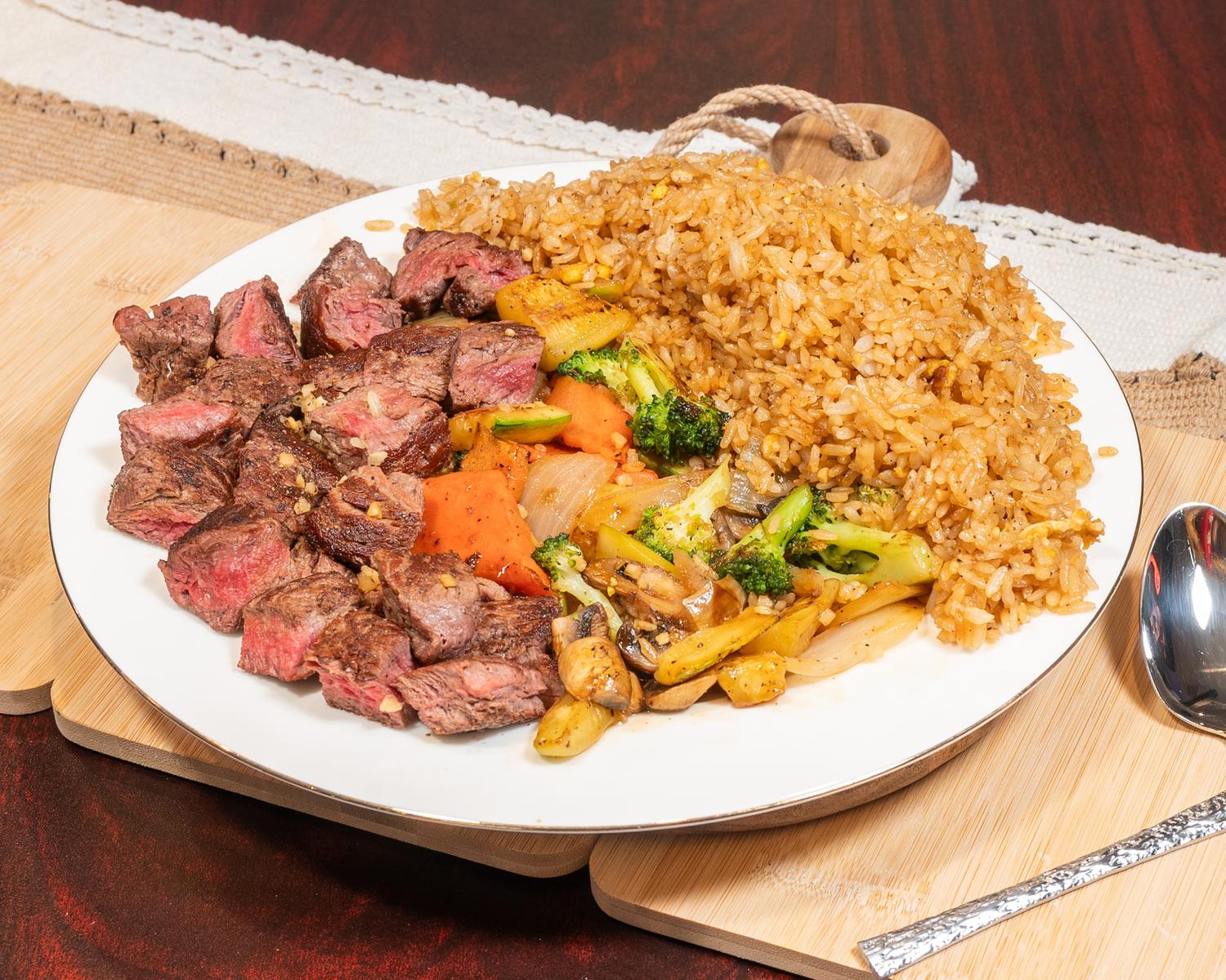 Medium-rare steak cubes paired with vegetable fried rice and seasoned mixed veggies at Ubin Sushi, a Japanese restaurant in Colorado Springs
