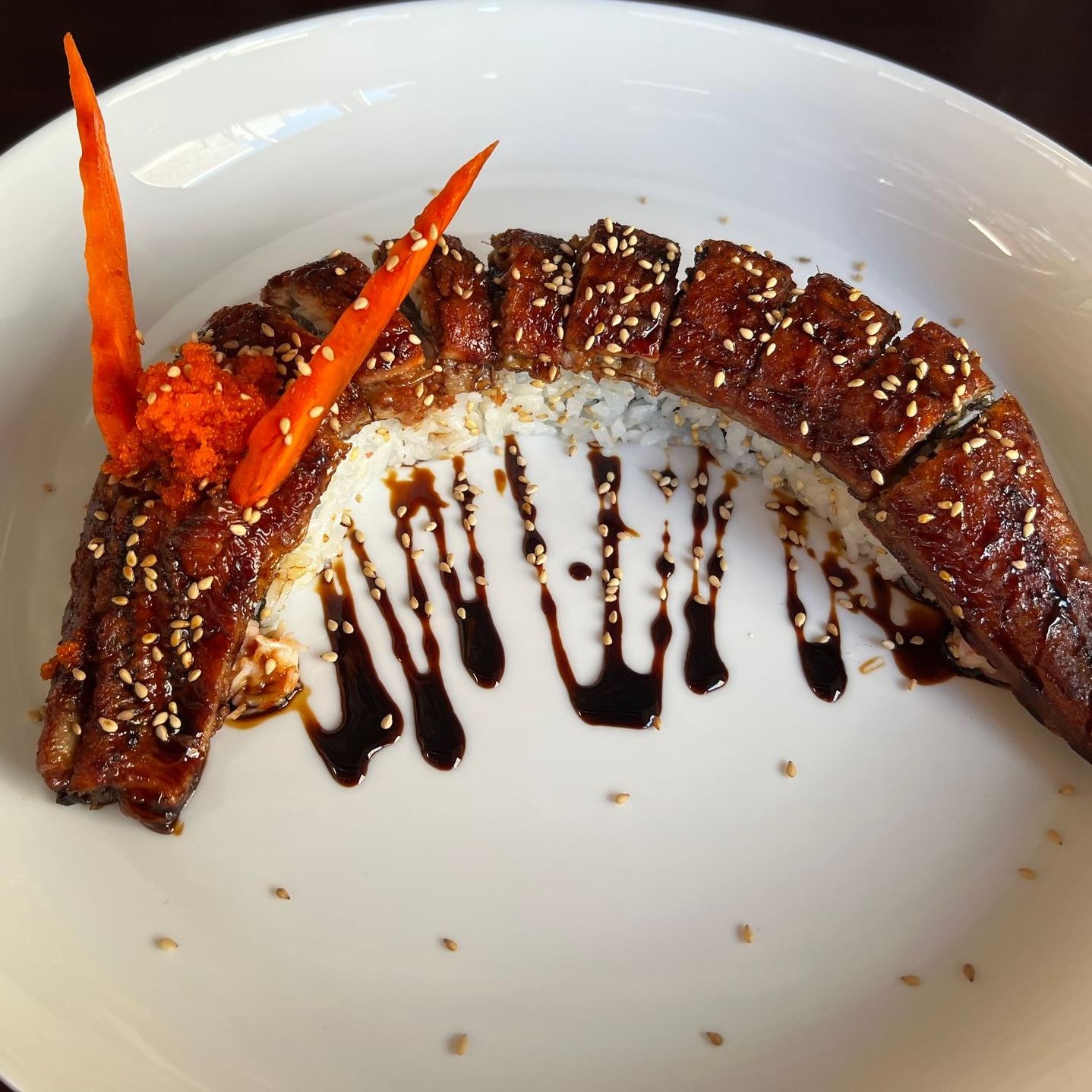 Curved unagi eel sushi roll glazed with teriyaki sauce and sesame seeds at Umami Sushi & Chinese Cuisine, an Asian Fusion Restaurant in Minneapolis
