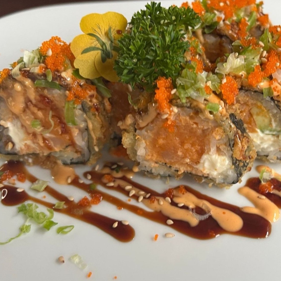 Deep fried crunchy sushi roll topped with orange tobiko roe and mixed green garnish at Umami Sushi & Chinese Cuisine, an Asian Fusion Restaurant in Minneapolis