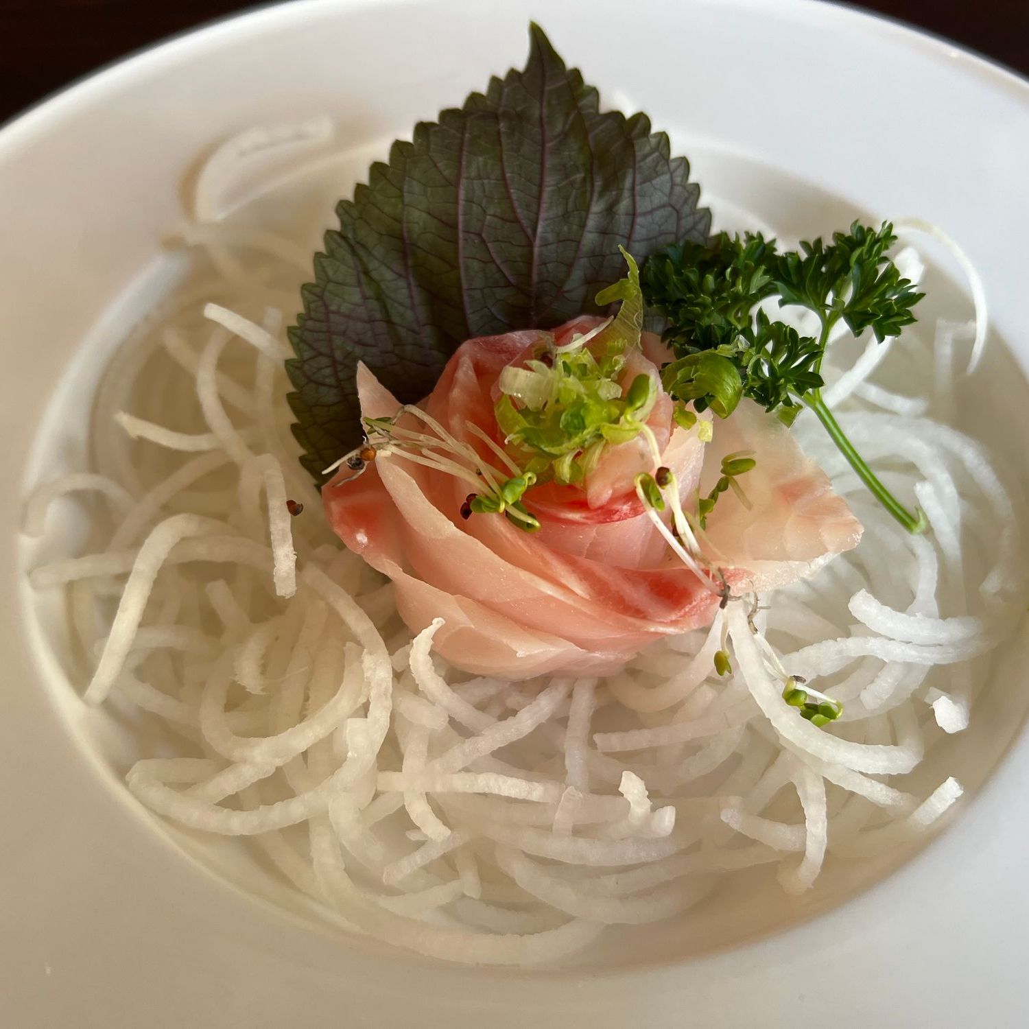 Rose-shaped white fish sashimi arranged on shredded daikon with herb garnish at Umami Sushi & Chinese Cuisine, an Asian Fusion Restaurant in Minneapolis