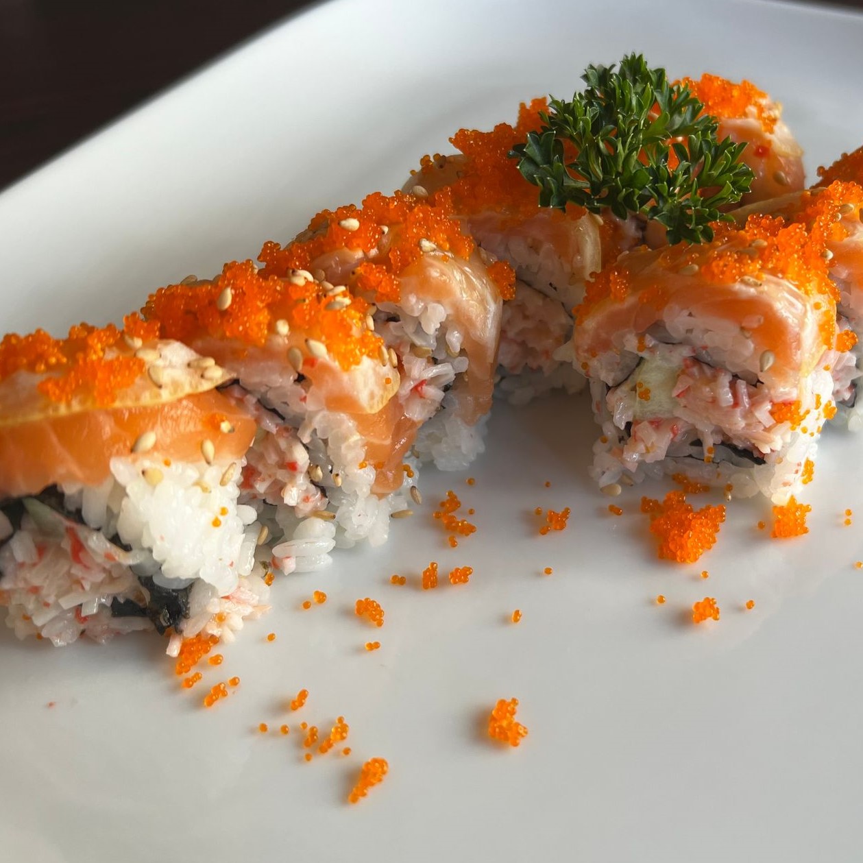 Salmon sushi roll topped with orange tobiko fish roe and white sesame seeds at Umami Sushi & Chinese Cuisine, an Asian Fusion Restaurant in Minneapolis