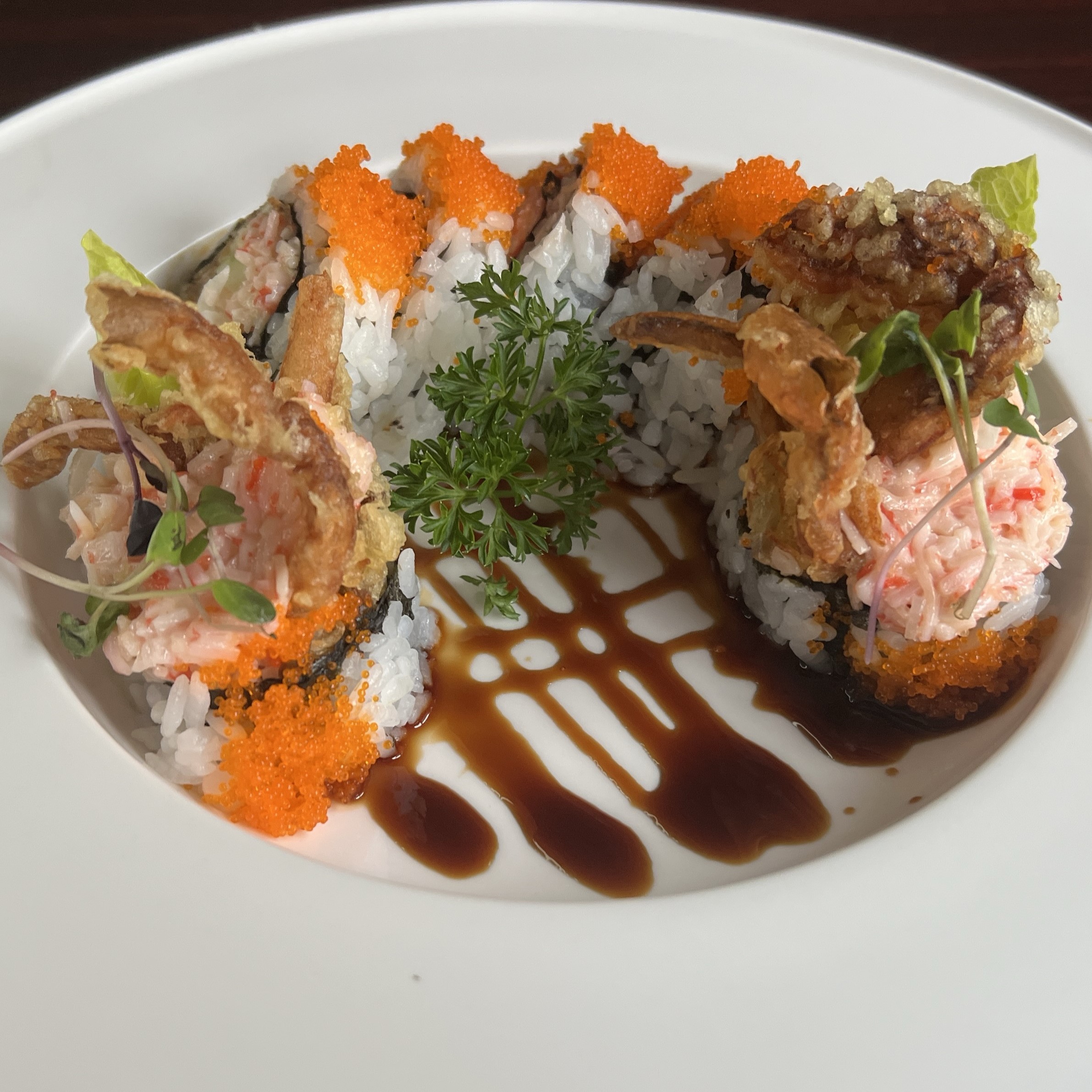 Tempura shrimp sushi roll topped with orange tobiko and teriyaki sauce drizzle at Umami Sushi & Chinese Cuisine, an Asian Fusion Restaurant in Minneapolis