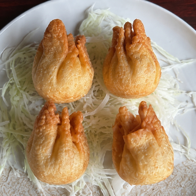 Four crispy deep-fried wonton pouches with shredded cabbage at Umami Sushi & Chinese Cuisine, an Asian Fusion Restaurant in Minneapolis