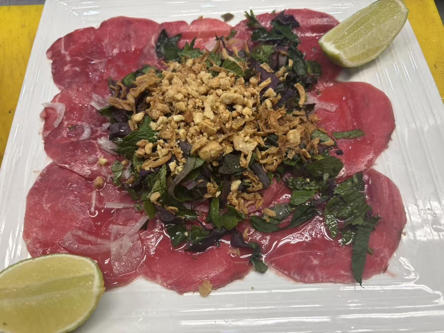 Beef carpaccio with herbs, nuts and lime wedges at Viet Quan Vietnamese Noodle House, a Vietnamese Restaurant in San Francisco