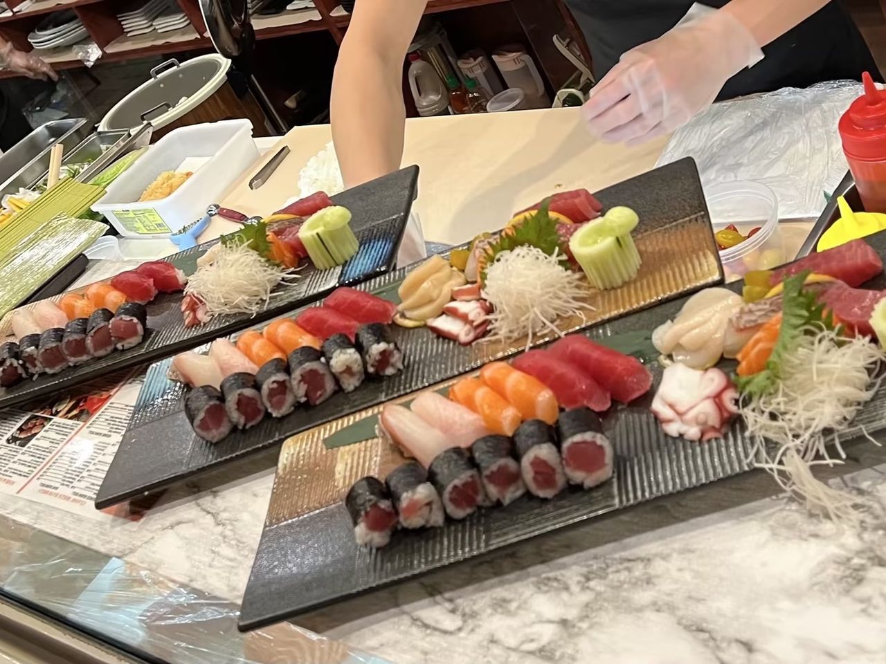 Assorted sushi, sashimi, and tuna rolls arranged on black serving plates