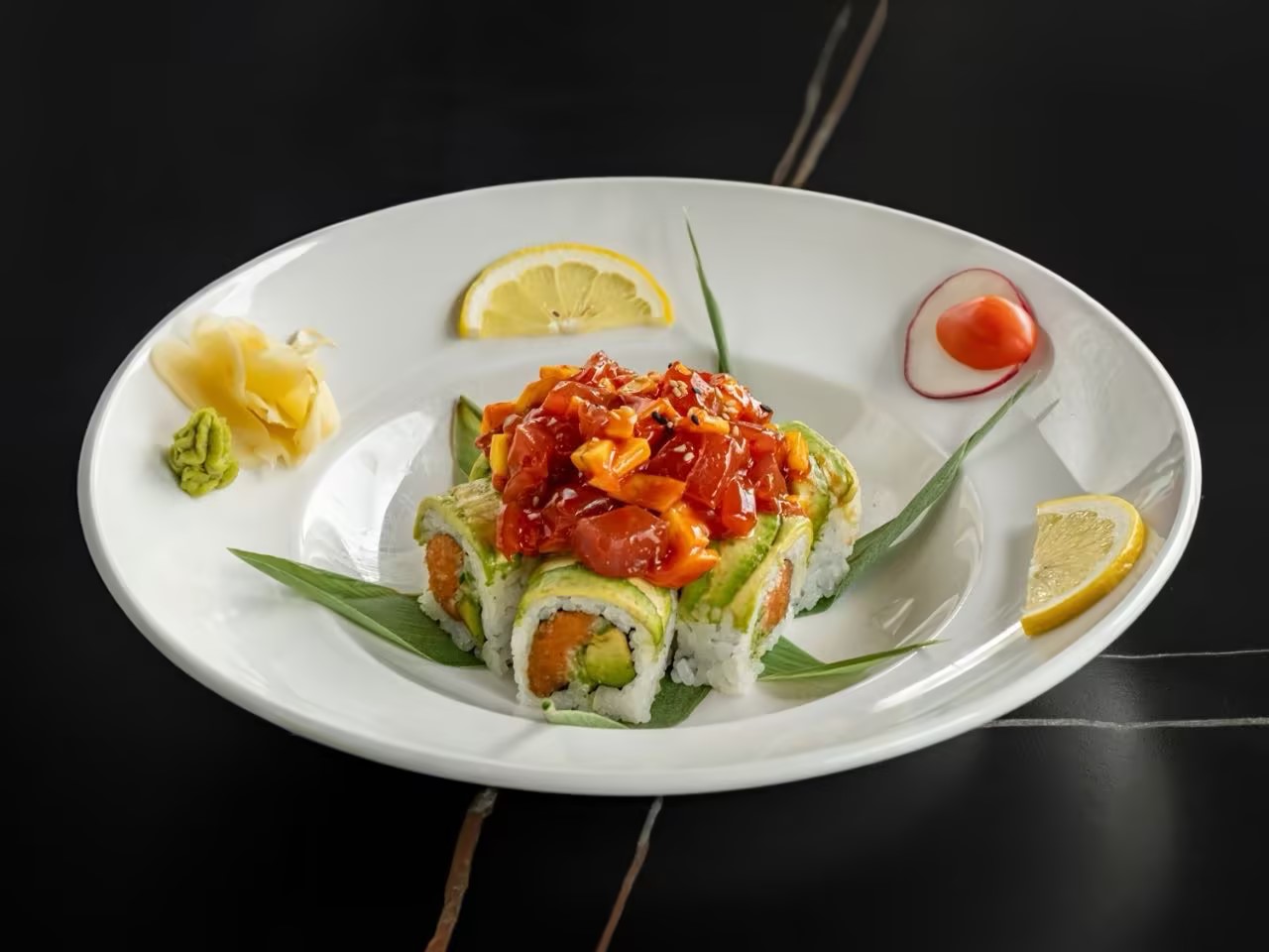 Sushi rolls topped with spicy tuna and avocado, served with ginger, wasabi, and lemon