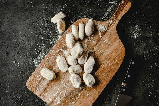 There are many dumplings placed on the wooden chopping board.