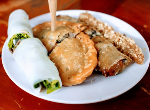 A plate of spring rolls 4 ways, including spring rolls with different styles and fillings, paired with wooden picks