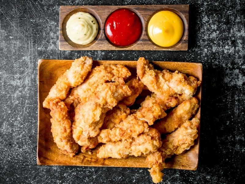 Breaded chicken tenders with three assorted dips on wooden tray at Which Wings, Fast Food Restaurant in Fort Worth
