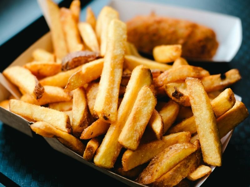 Thick-cut golden french fries packed in paper box at Which Wings, Fast Food Restaurant in Fort Worth